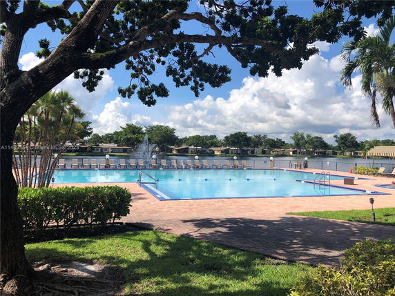 Outdoor swimming pool area with lounge chairs and trees around.