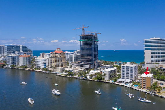 Aerial view of a coastal cityscape with high-rise buildings and boats on water.