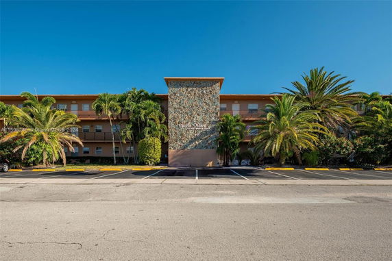 Front view of a multi-story building with a stone facade and palm trees.