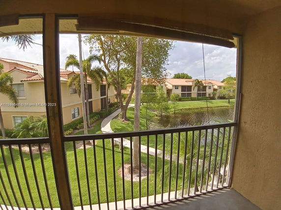 View from a balcony overlooking a landscaped area with a pond and surrounding residential buildings.