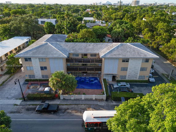Front view of a multi-story residential building with a parking area and balconies.