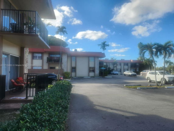 Outdoor parking area in front of a two-story building with balconies.