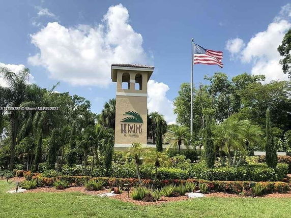 Front view of a tall structure with a sign reading 'The Palms' and an American flag nearby.