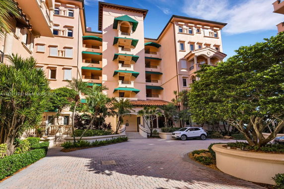 Front view of a multi-story apartment building with balconies and green awnings.