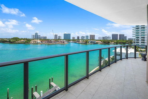 Panoramic view from a balcony overlooking a body of water and distant modern buildings.