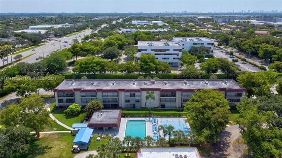 Aerial view of a residential building with a swimming pool and surrounding greenery.