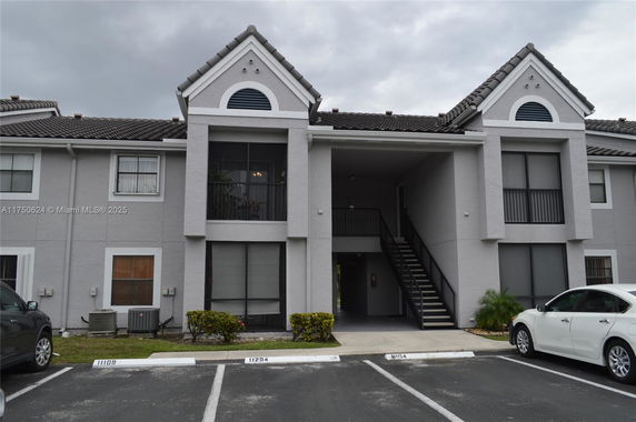 Front view of a two-story residential building with a staircase and parking area.
