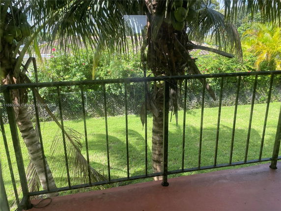 View of a grassy area and palm trees from a balcony.