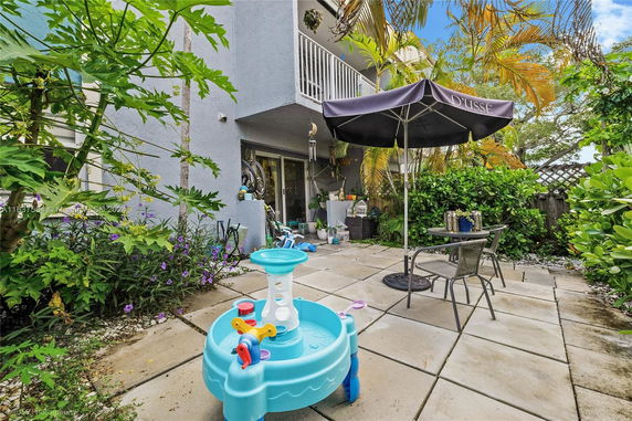 Patio area with toys, outdoor furniture, and lush greenery.