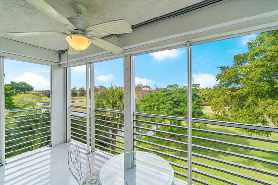 View from a balcony with metal railings overlooking a grassy landscape and trees.