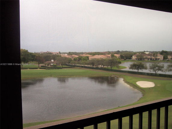 View from building showing a golf course, pond, and houses in the distance.
