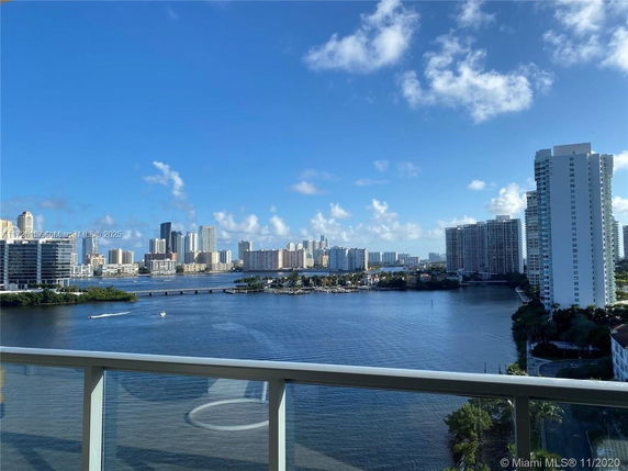 Panoramic view of waterfront cityscape with high-rise buildings and blue sky.