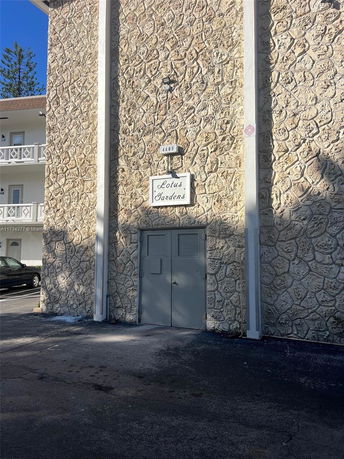 Front view of a building with a textured stone facade and a sign reading 'Lotus Gardens.'