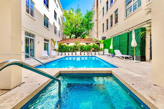 Outdoor swimming pool area with lounge chairs and greenery.