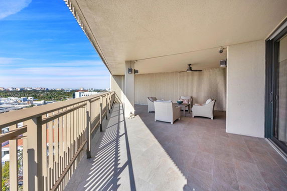 Outdoor balcony with seating area and view of surrounding cityscape.
