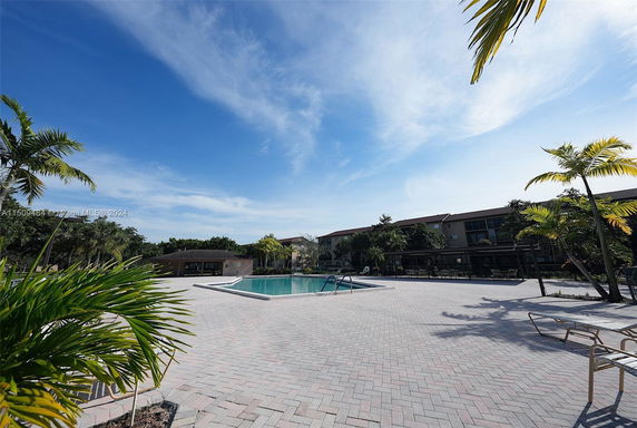 Outdoor area featuring a swimming pool with surrounding patio and tropical plants.