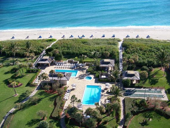 Aerial view of beachfront property with multiple swimming pools and surrounding landscape.