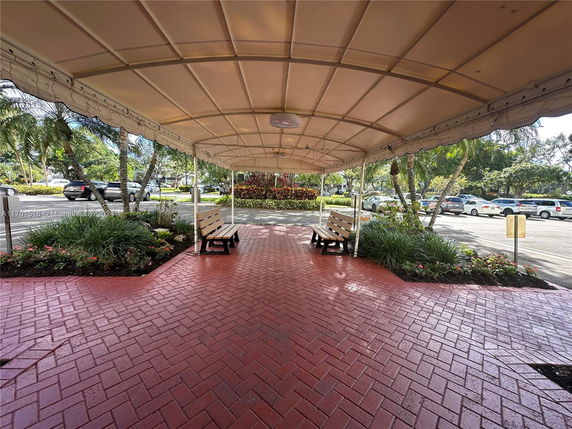 Covered outdoor walkway with seating adjacent to a parking area.