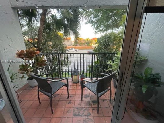 View from a balcony with a railing and two chairs overlooking a street and trees.