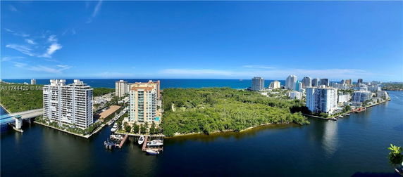 Panoramic view of waterfront area with high-rise buildings and lush greenery.