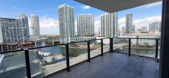 View from a balcony overlooking a cityscape with modern high-rise buildings and a river.