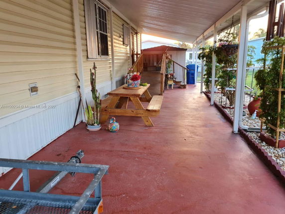 Covered outdoor walkway with plants and a picnic table next to a building.