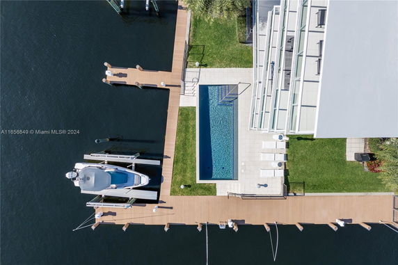 Aerial view of a modern waterfront property with a swimming pool and dock.