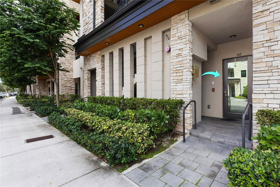 Front view of a modern building entrance with stone facade and glass door.