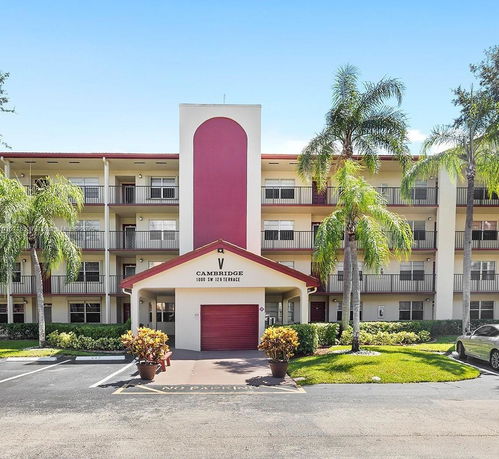 Front view of a multi-story residential building with balconies and palm trees.