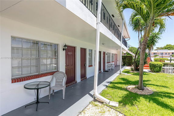 Front view of a two-story apartment building with an exterior corridor and doors leading to individual units.
