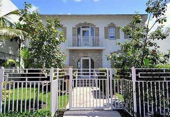 Front view of a two-story house with a balcony and gated entrance.