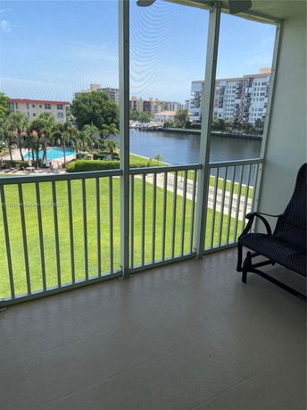 View from a balcony showing a swimming pool and residential buildings near a body of water.