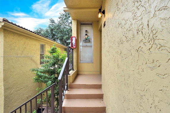 Front staircase leading to an entrance of a beige textured building with a window.