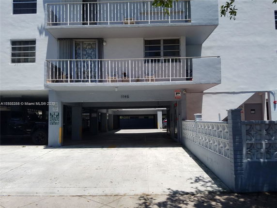 Front view of a multi-story building with balconies and a covered parking area.