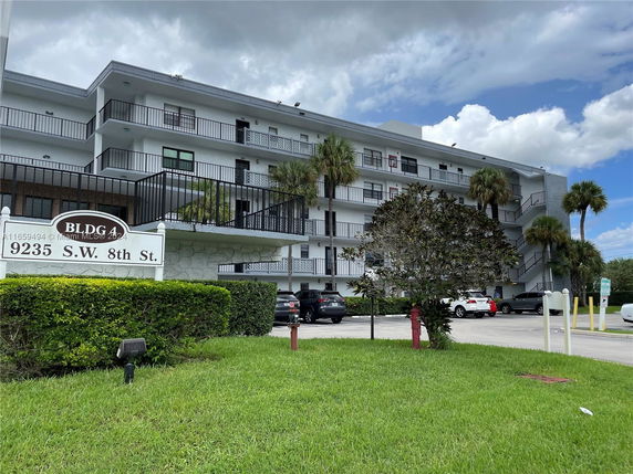 Front view of a multi-story residential building with balconies and parking area.