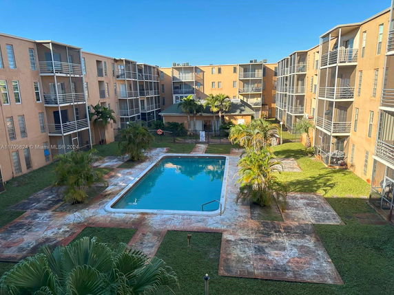 View of a courtyard with a swimming pool surrounded by a multi-story apartment building.