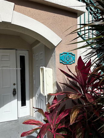 Front entrance of a building with an arched design above the door and a unit number 104 displayed.