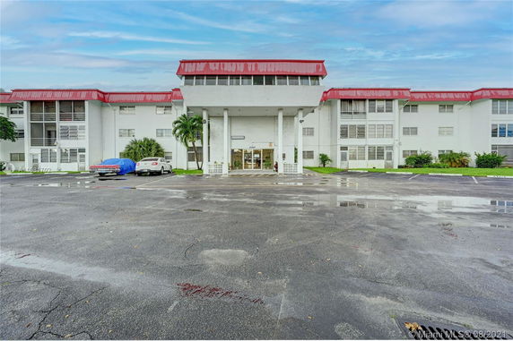 Front view of a multi-story building with red trim and a large entrance area.