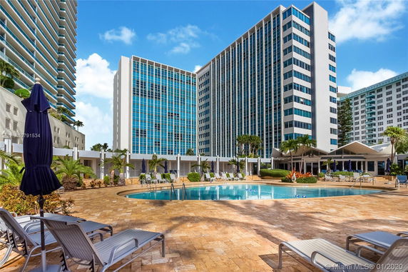 Front view of a tall modern building with a swimming pool in the foreground.