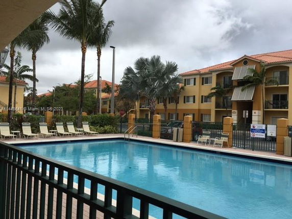 Outdoor swimming pool with lounge chairs surrounded by residential buildings.