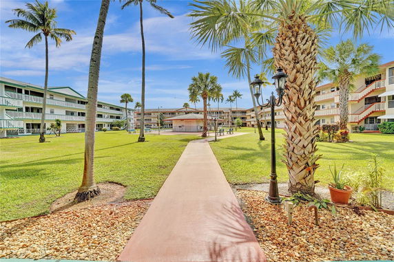 Front view of multi-story residential buildings with balconies and palm trees.