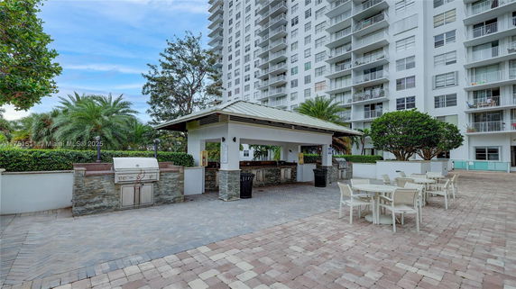 Outdoor area with a dining setup and a view of a tall residential building.