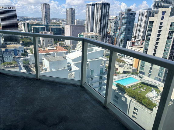View from a building balcony showing surrounding skyscrapers and a rooftop swimming pool.