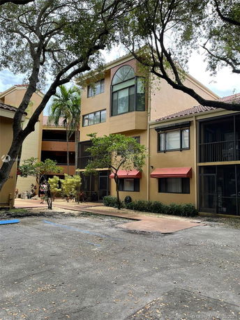 Front view of a multi-story apartment building with large windows and red awnings.