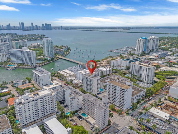 Aerial view of a coastal city with multiple residential buildings and a body of water with boats.