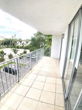 Balcony view from a building overlooking a parking lot and trees.