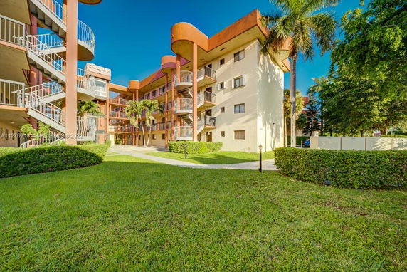 Front view of a multi-story residential building with balconies and a spiral staircase.