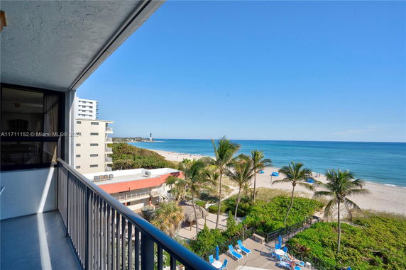 View from a building balcony overlooking the beach and ocean.