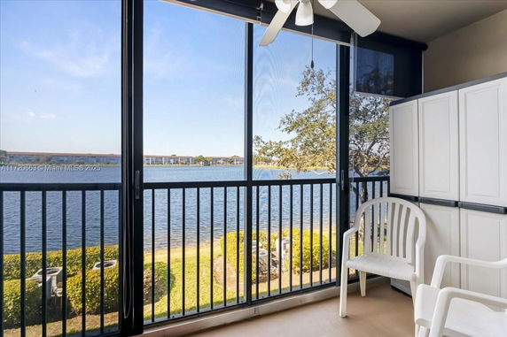 Panoramic view of a lake and buildings seen from a balcony with chairs and storage cabinets.