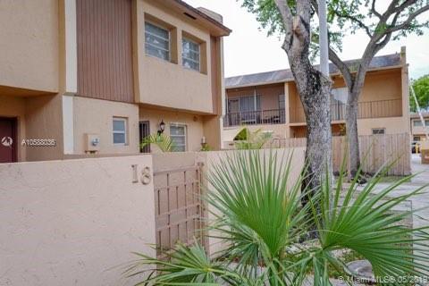 Front view of a two-story residential building with balconies and a fenced entry.